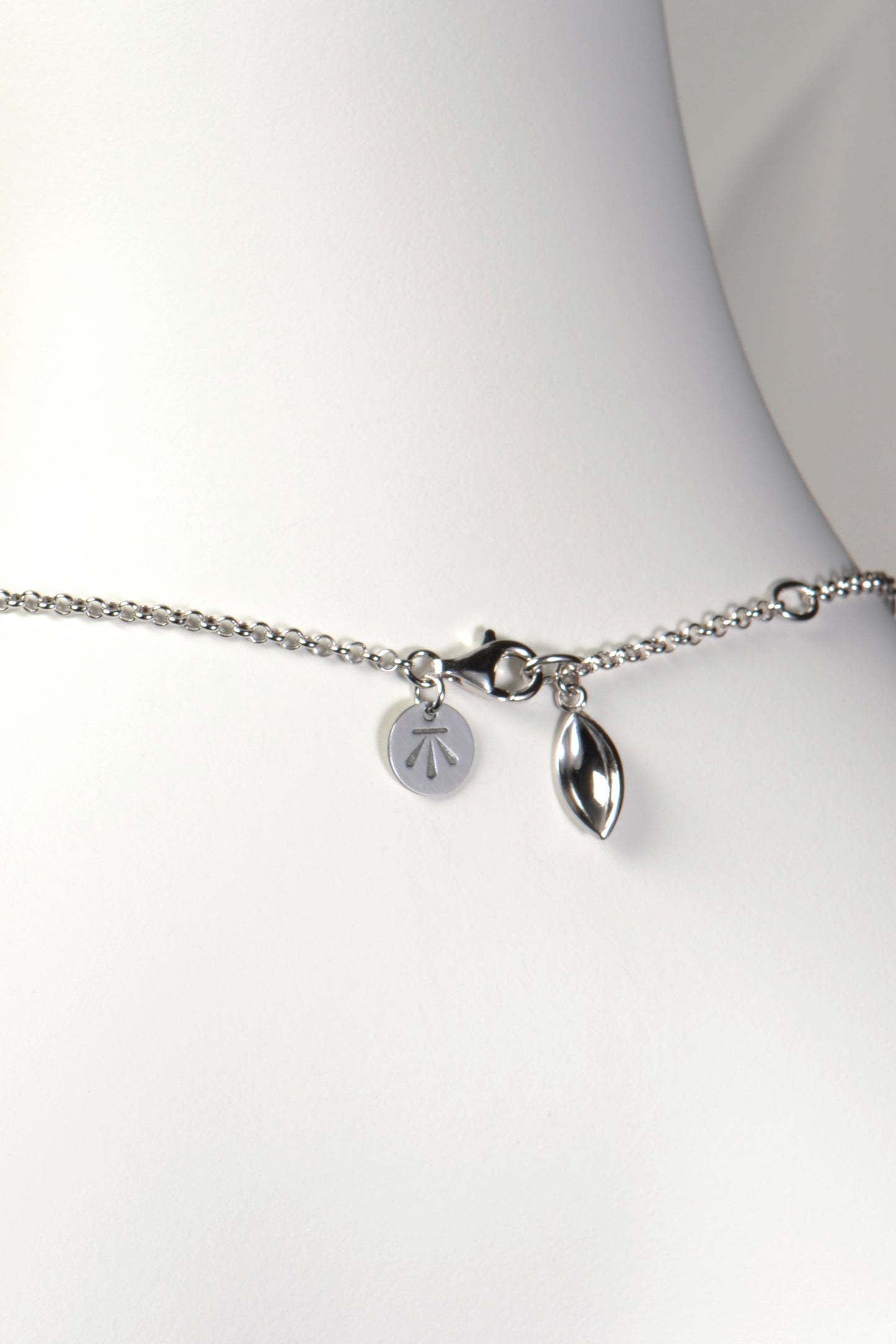 sterling silver modern necklace with a seed shaped charm detail that hangs at the clasp. Christine Sadler