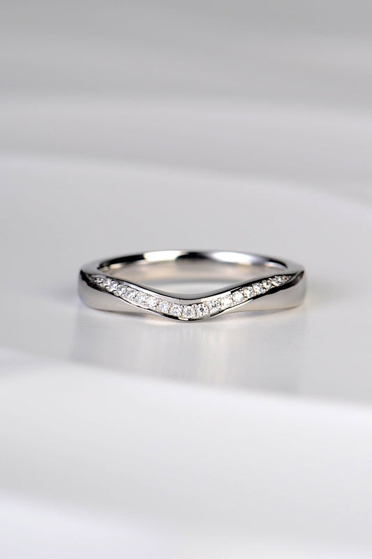 U shaped wedding ring that dips at the front in a sculptural carved way and which has a ribbon of brilliant cut diamonds following the curve