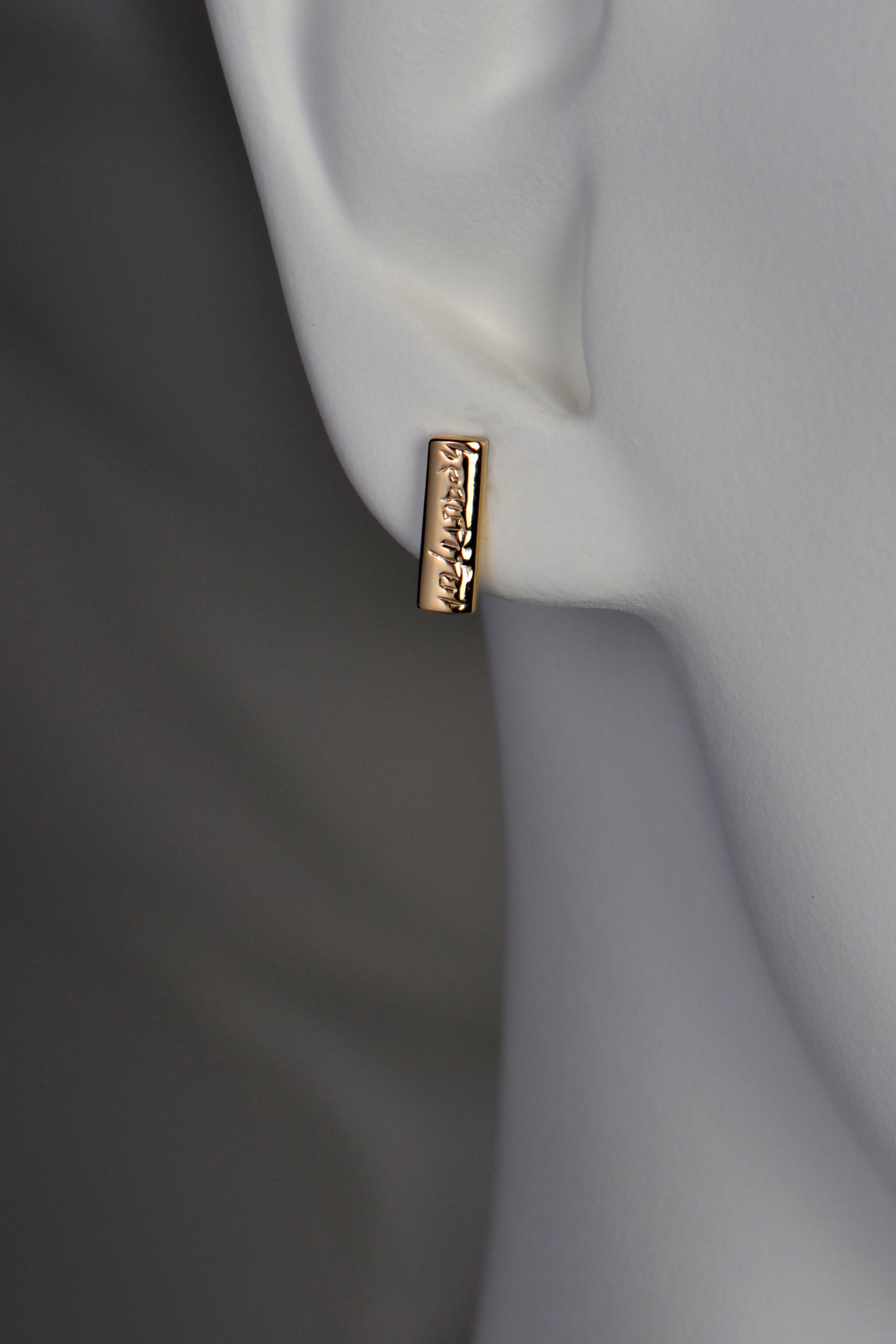 small handmade gold studs that are engraved with the word "beautiful"