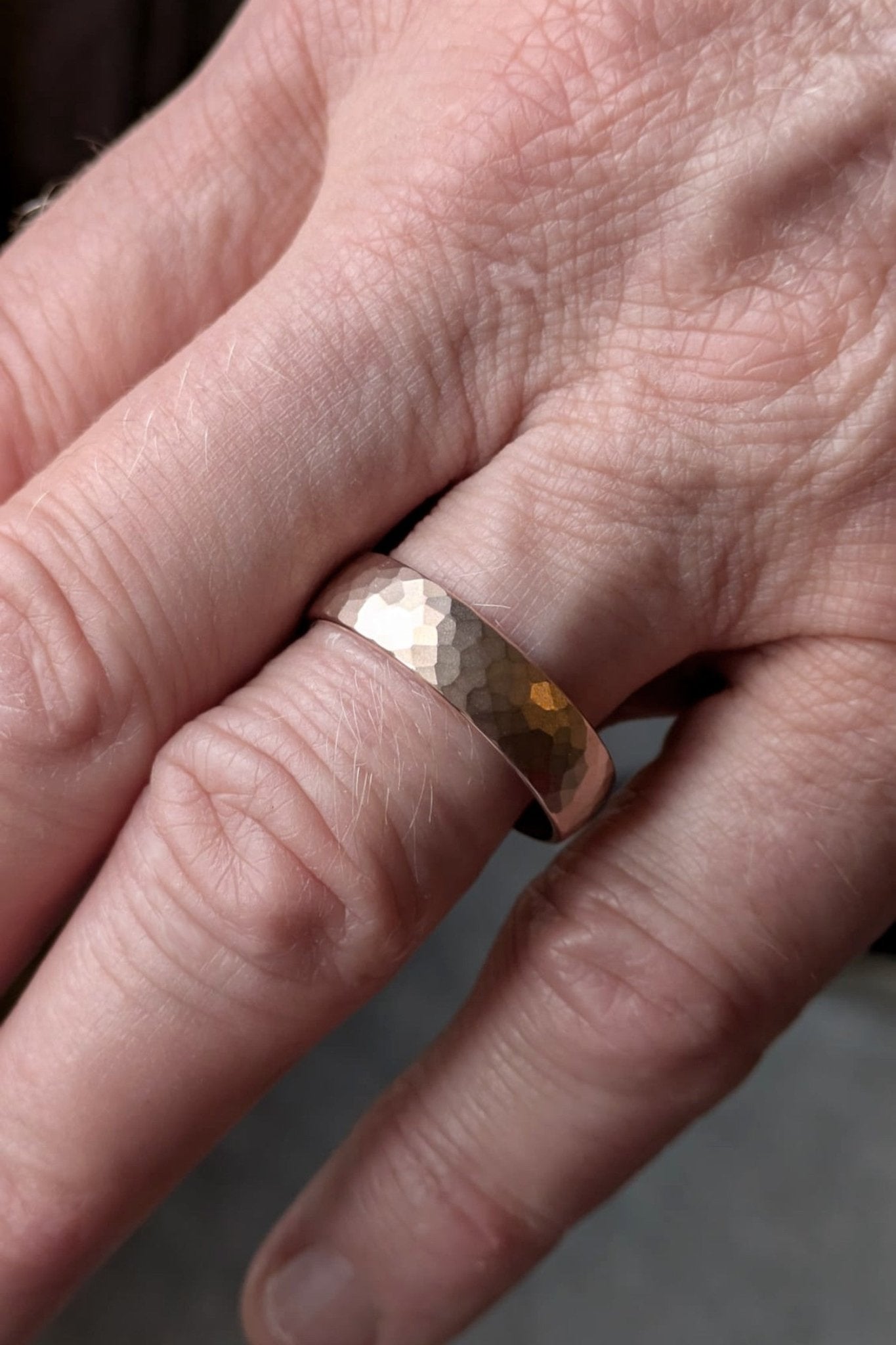 6mm hammered matt brushed 18ct rose gold gents wedding ring shown on a man’s hand, understated and timeless design by Christine Sadler Unforgettable Jewellery, handmade in the UK