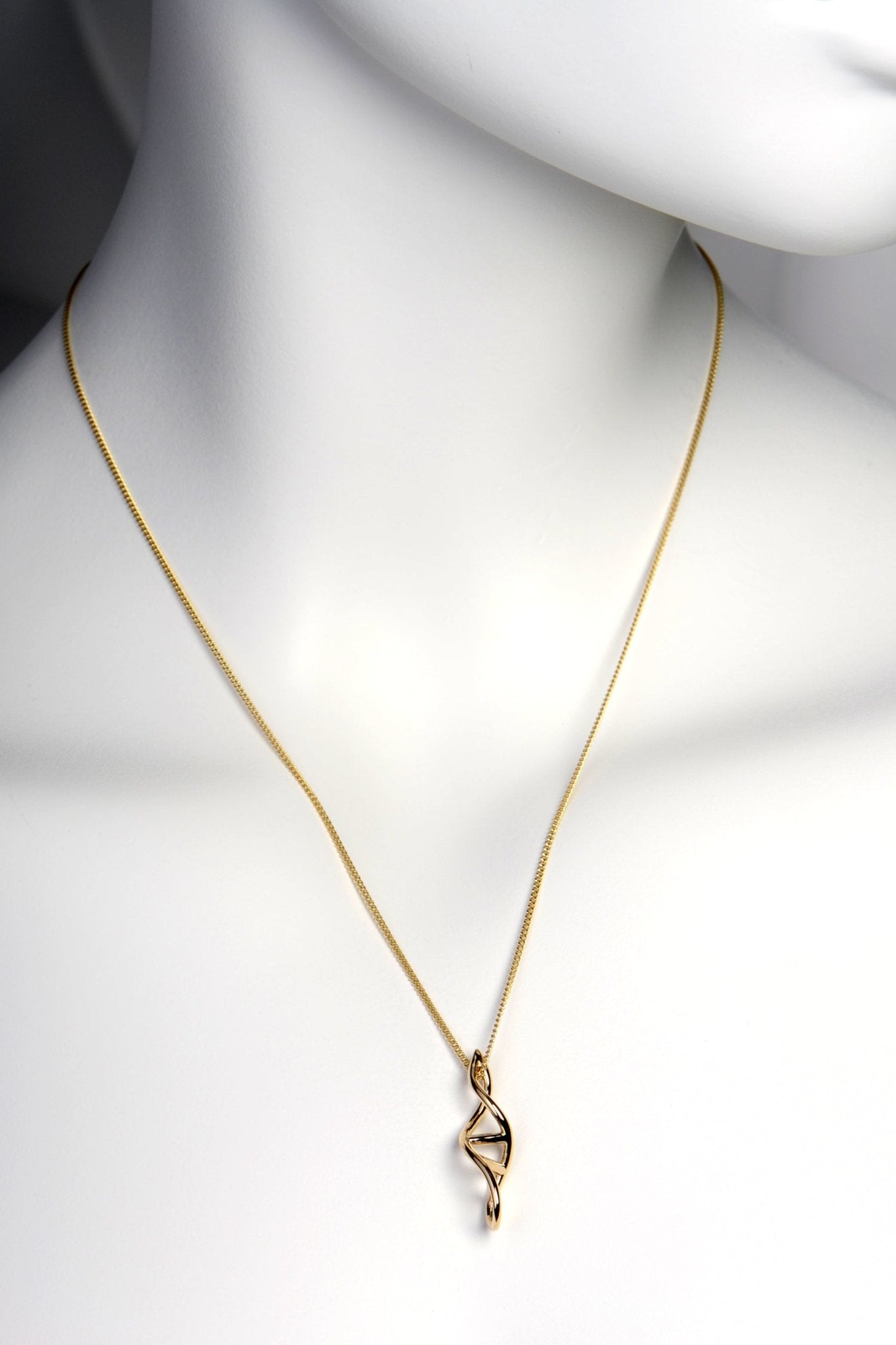 Gold DNA pendant necklace shown on mannequin to illustrate scale and elegant chain length.
