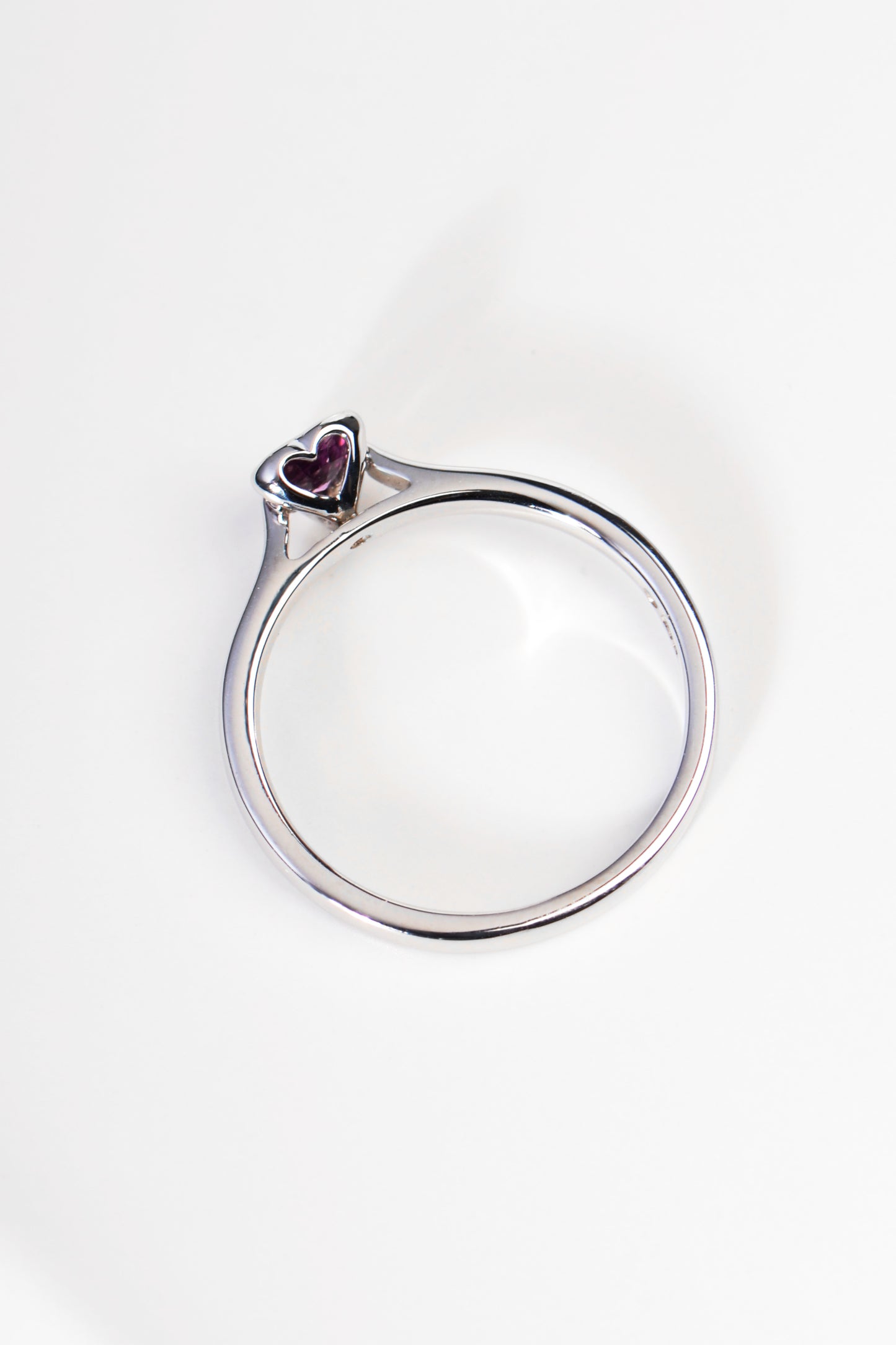 white gold ring with heart shaped cut out on side of ring setting