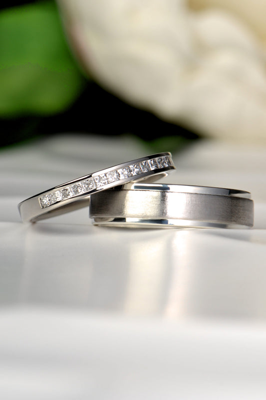 Princess cut band for a woman next to a platinum and silver gents wedding ring - his and hers wedding rings from Christine Sadler