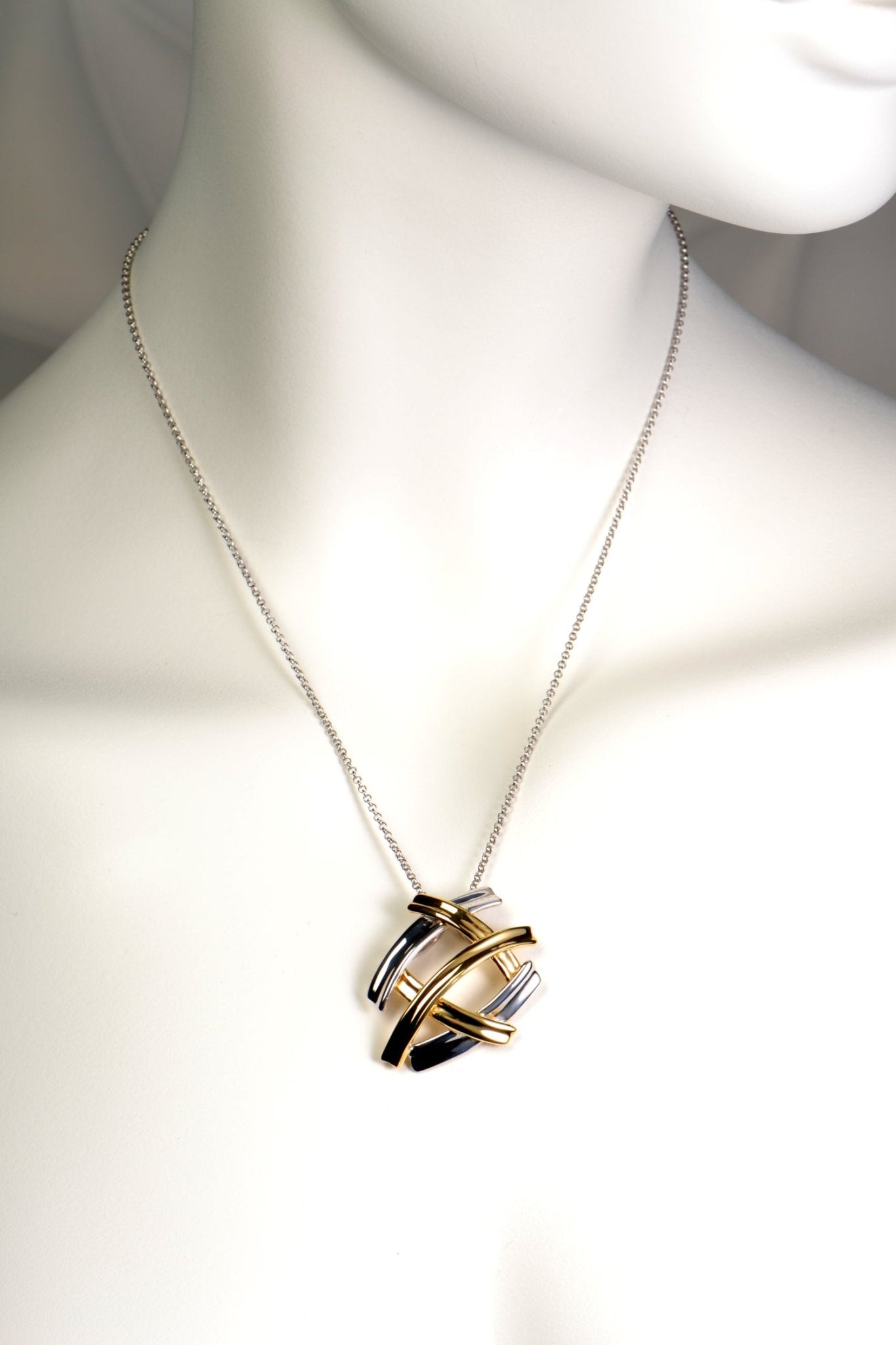 five criss cross bands create a pendant that looks like several large silver and gold kisses. The necklace in silver with gold vermeil.