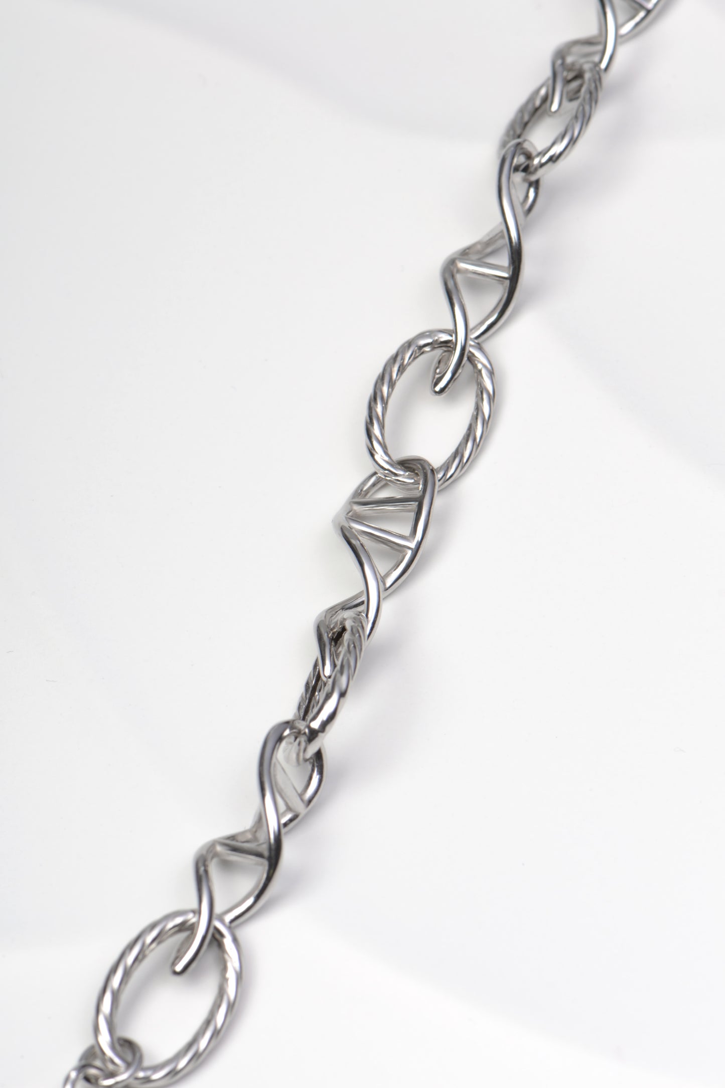 Sterling silver oval link shaped like a fine thread, representing the invisible bonds between people alternating with double helix shaped links on a white background