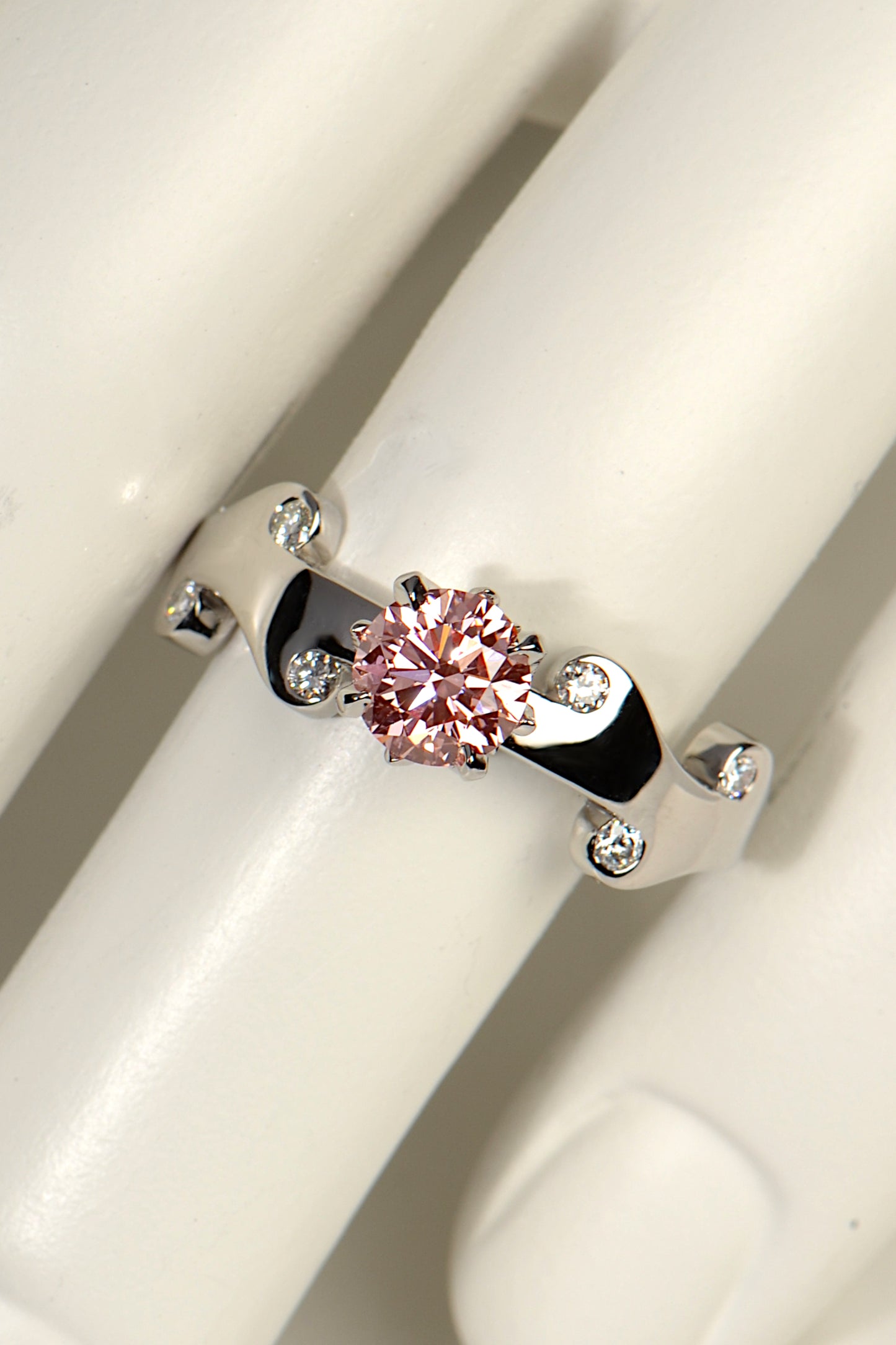 Gorgeous rose pink lab diamond ring set with a cental large round pink lab diamond and six small white lab diamonds in the platinum band. An exclusive design by scottish jewellery designer Christine Sadler.