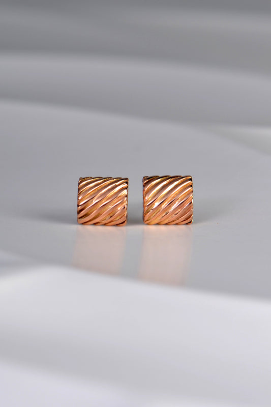 handmade designer rose gold earrings inspired by ditali pasta. It is a curved rectangular small stud earring with diagonal polished ridges
