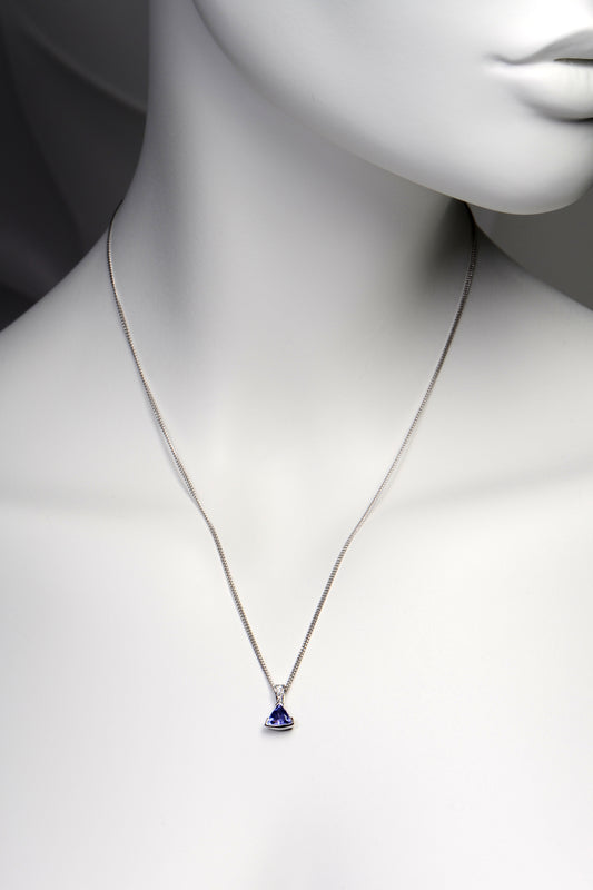 handmade high quality tanzanite and diamond designer necklace shown on a model. The pendant hangs about two inches below the collar bones