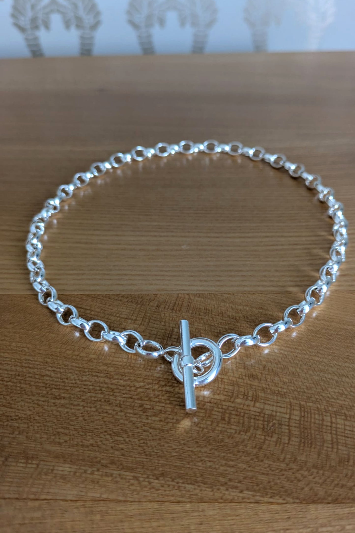 Sterling silver T-bar necklace with soldered links displayed on natural wood surface – secure and stylish design