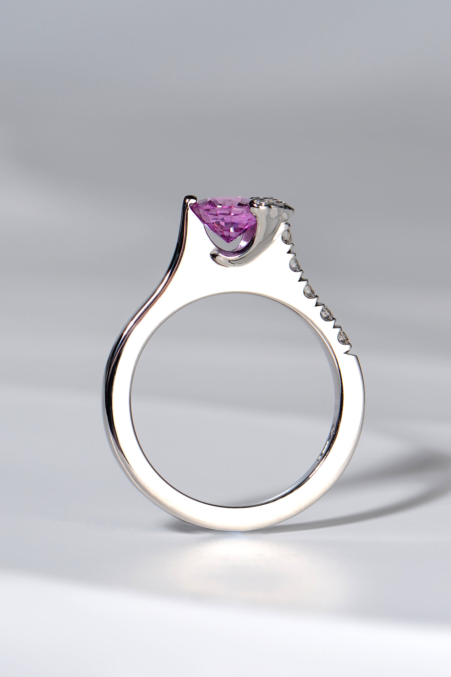 designer platinum diamond and pink sapphire ring that has the stone set so you can see the gemstone side on, like a tension set ring