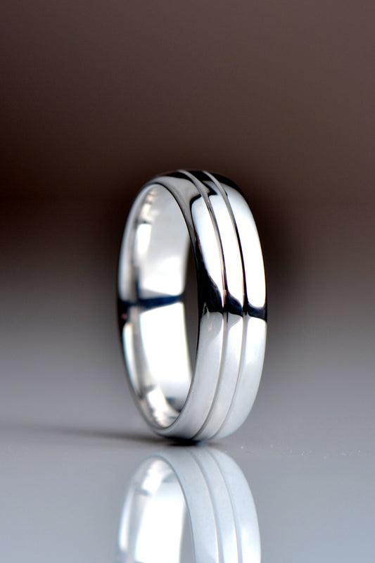 Highly polished modern 6mm wide platinum wedding ring with two grooves cut in as a surface detail
