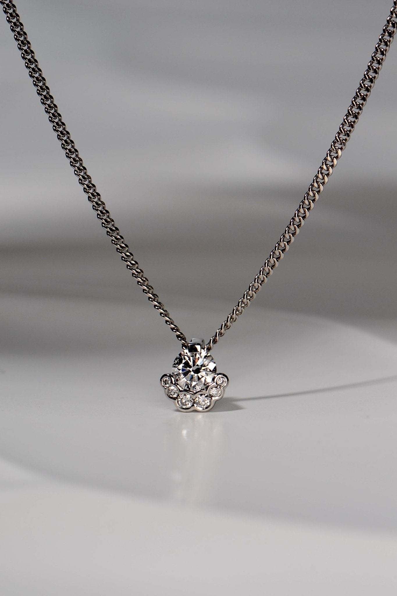 platinum designer lab grown necklace that is special and different set with one larger central stone surrounded on the bottom half by six smaller stones. The design is inspired by the Scottish Fairy Pools on the Isle of Skye exclusively available from Christine Sadler