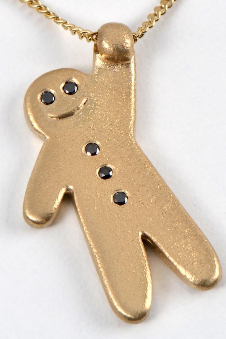 cute gold smiling gingerbread man with black diamond eyes and three balck diamond buttons hanging from a gold chain by British jewellery designer Christine Sadler