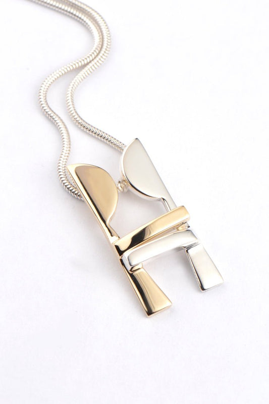 Modern gold and silver pendant that has two people kissing and embracing each other that move apart and come back together, a unique design by British jewellery designer Christine Sadler