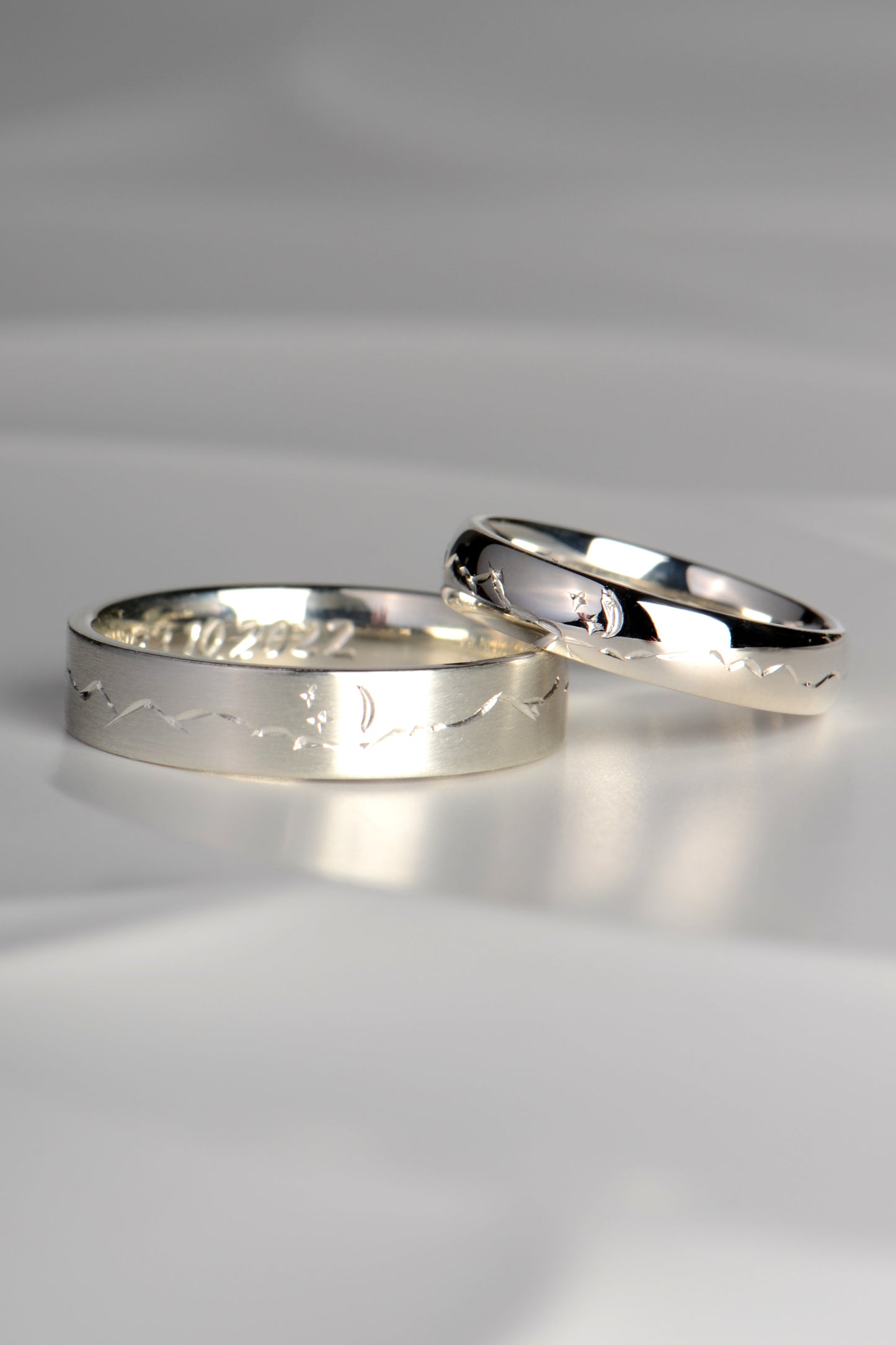 wedding rings for a man and a woman with hand engraved mountain design and a moon and stars