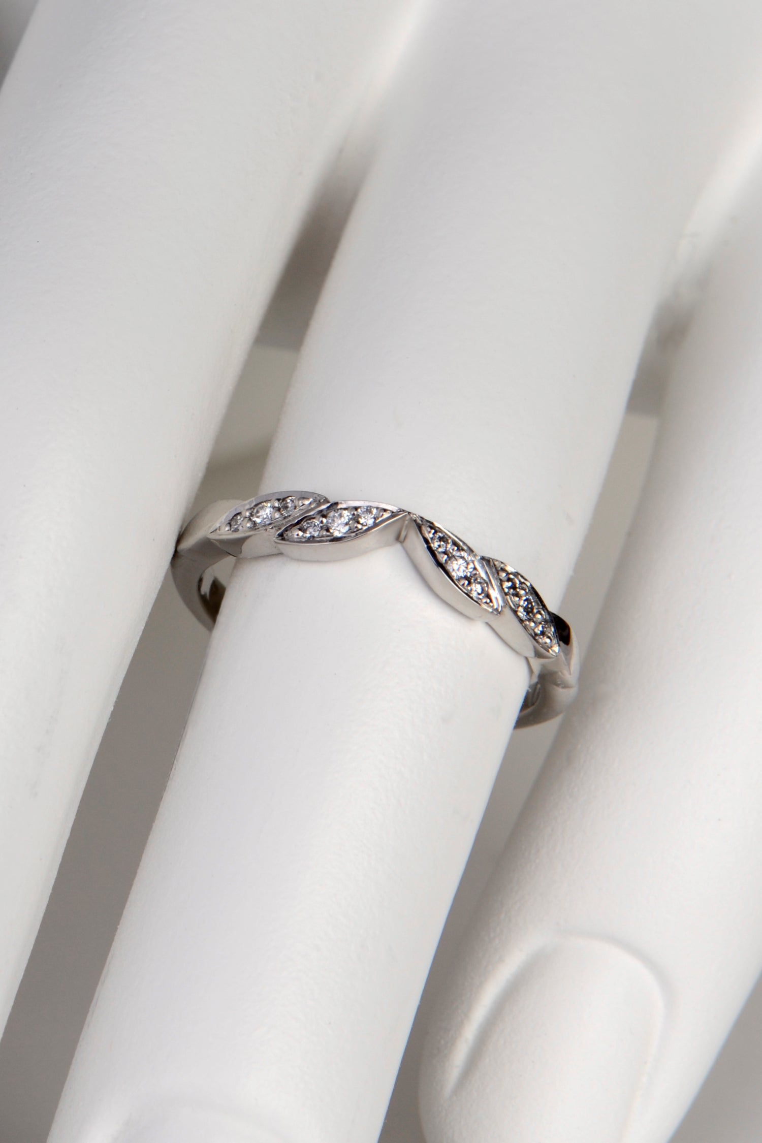 handmade platinum ring with a V shaped dip at the front created by four leaf shaped details set with diamonds. The V shape allows an engagement ring to slot into the space at the front.