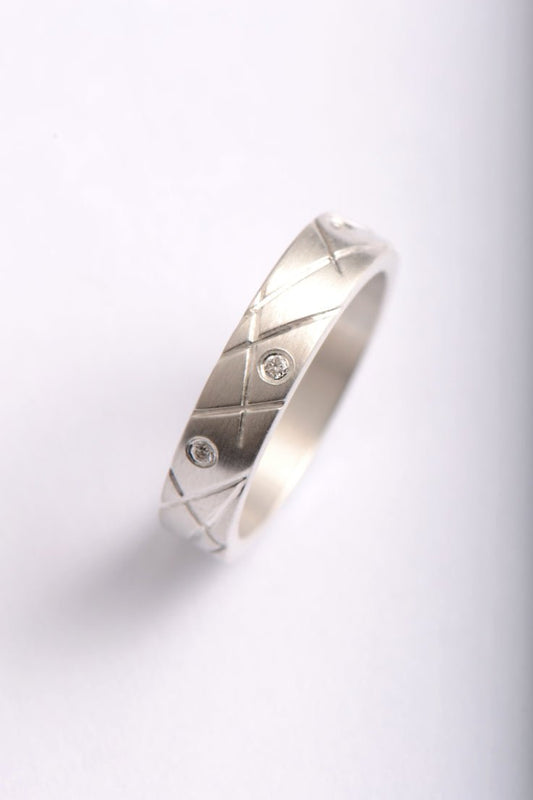 fun handmade silver and diamond ring design inspired by 100's and 1000's sprinkles on cakes. The ring has criss cross lines engraved on the band with seven diamonds scattered all the way round by contemporary jewellery designer Christine Sadler