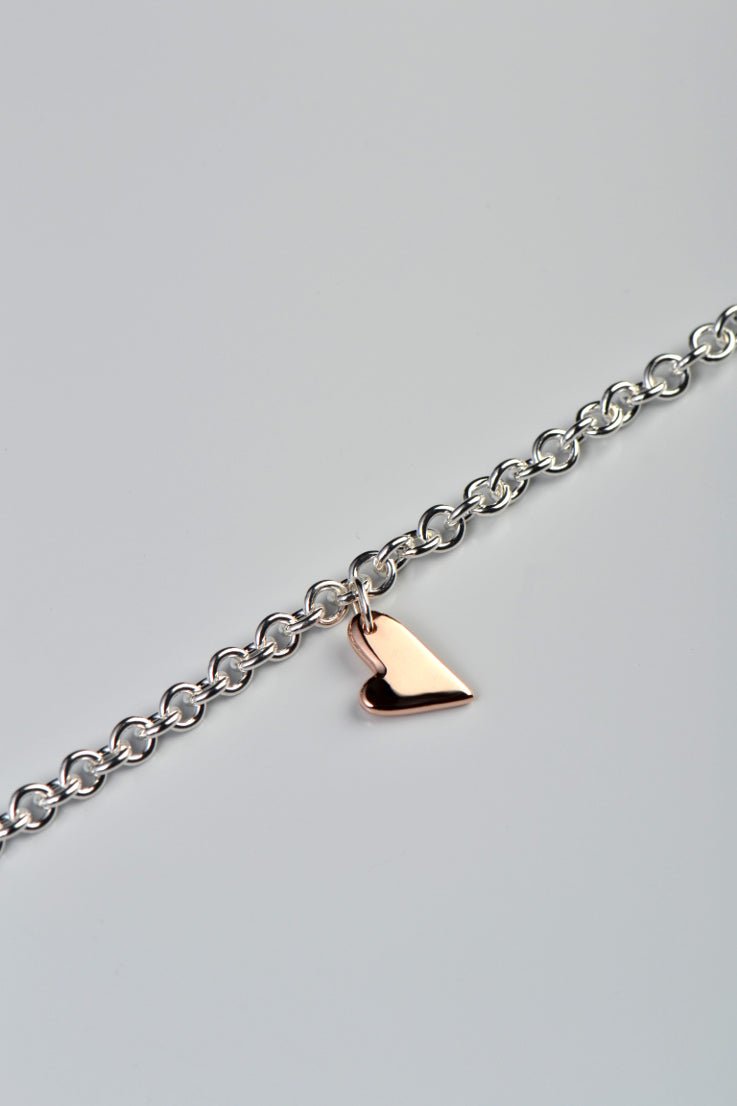 Sterling silver bracelet with two highly polished 9ct rose gold hearts — large front heart and small heart by secure lobster clasp, From The Heart collection shown on a white background