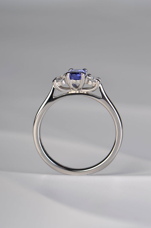 Three stone tanzanite and diamond platinum engagement ring with stones raised up so that it will sit perfcctly next to a straight wedding ring. This ring is made in the UK