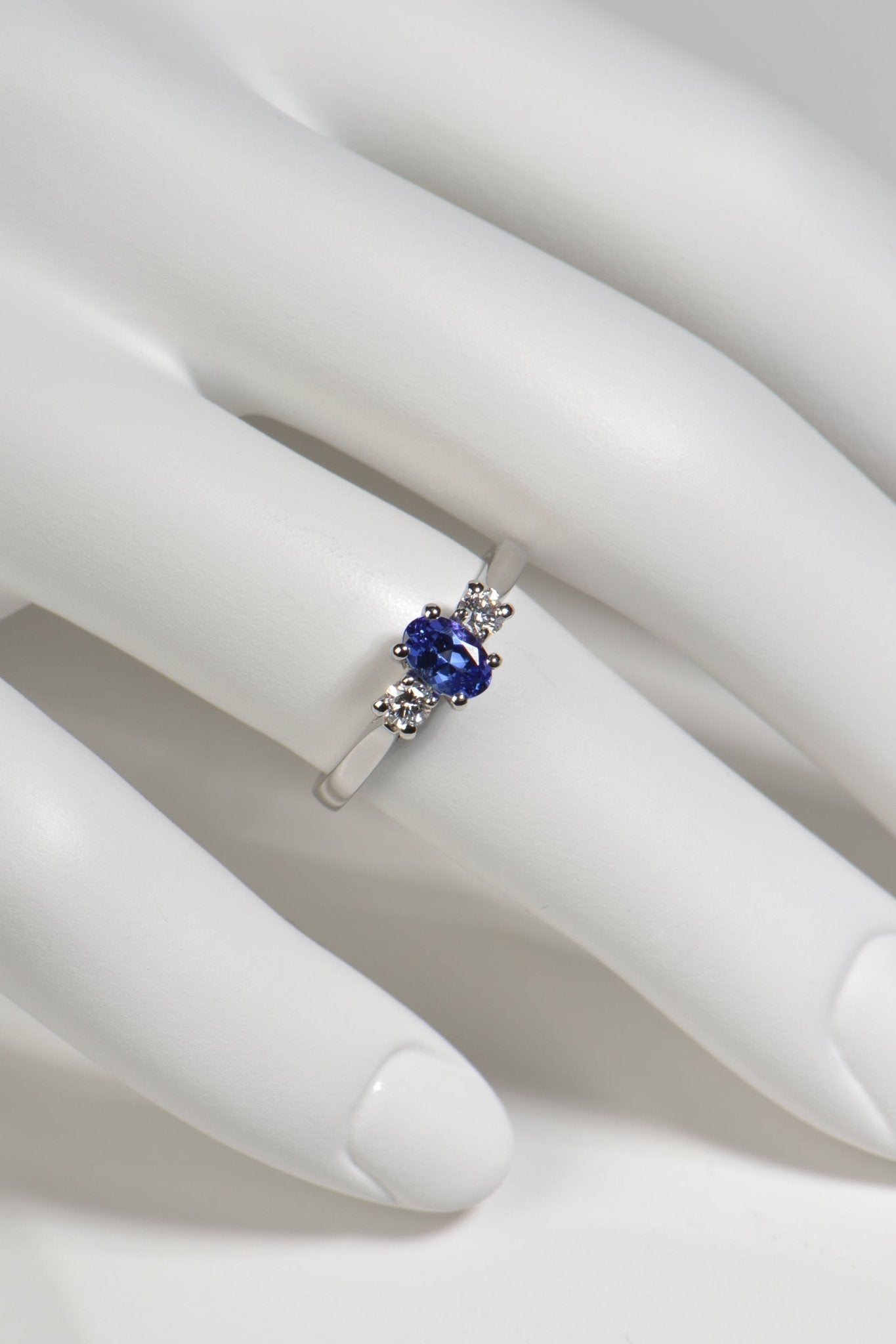 elegant tanzanite and diamond three stone ring shown worn on a finger