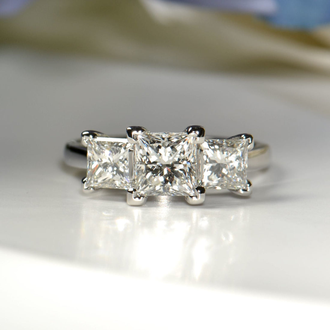 A three stone pirncess cut ring made from a solitaire and a pair of diamond earrings
