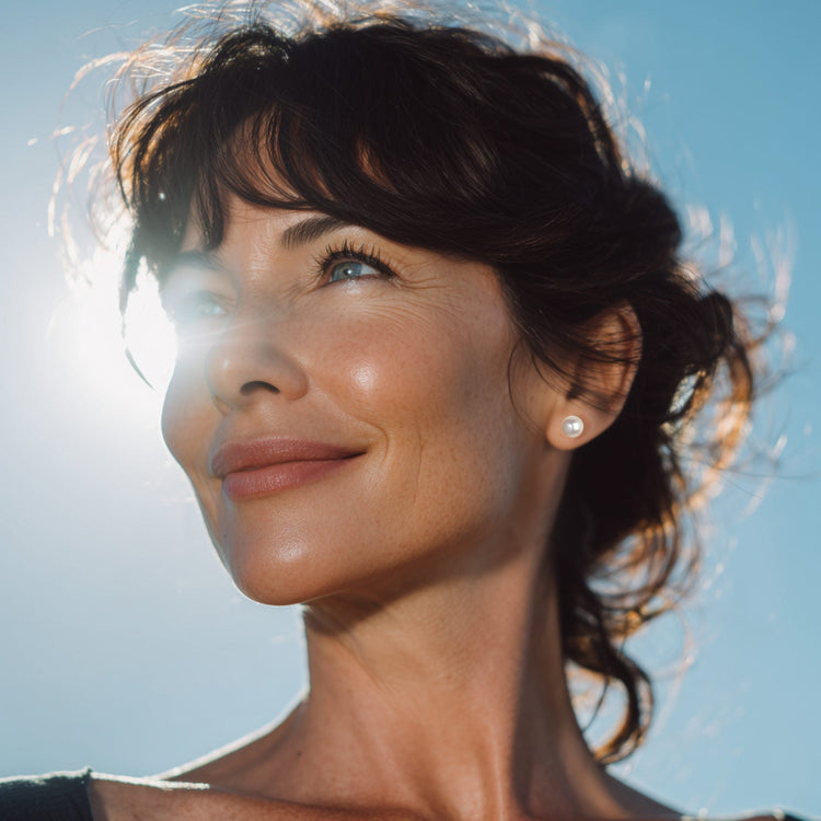 Woman wearing an 8mm white pearl earring with blue sky behind her - 30th wedding anniversary jewellery from Christine Sadler