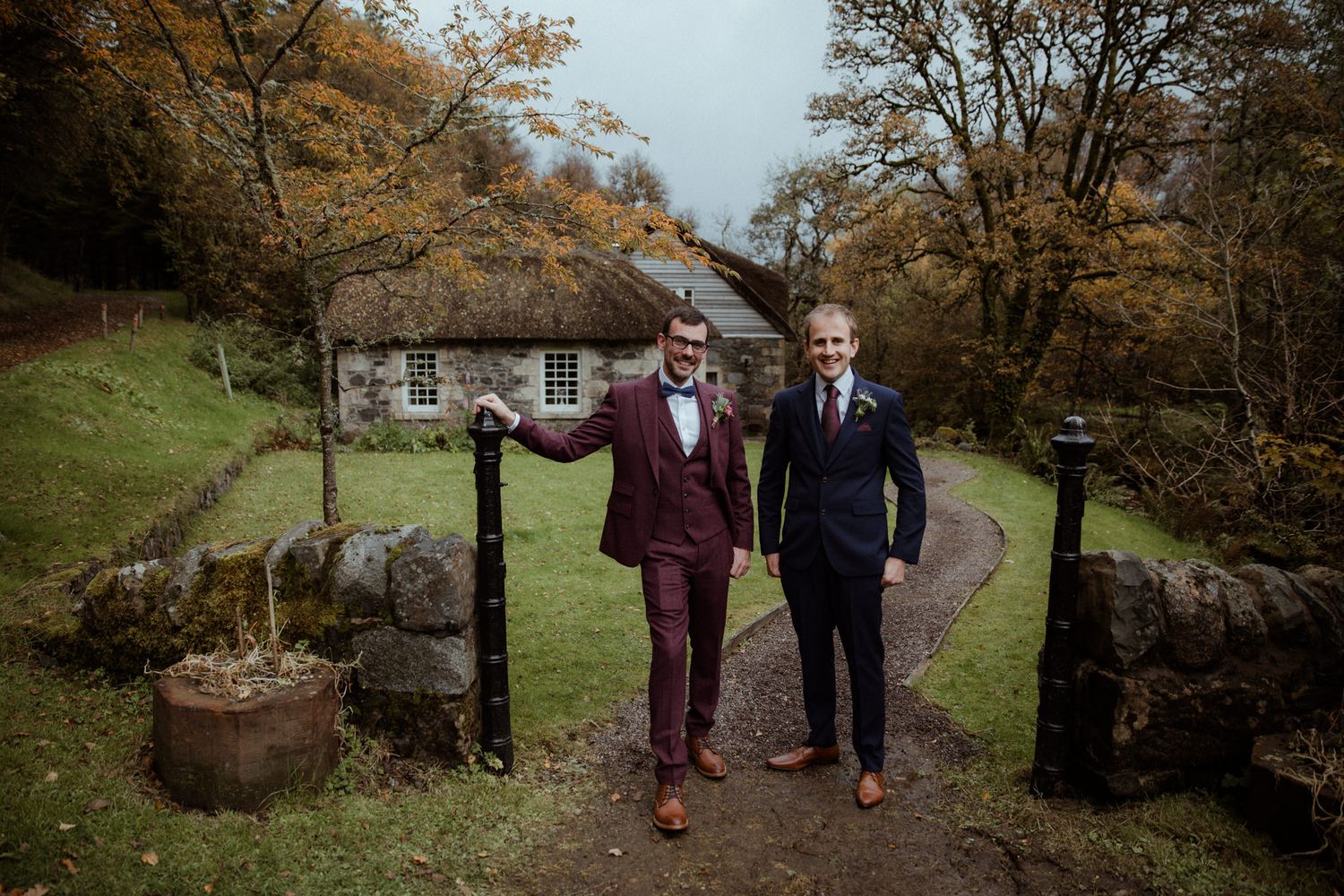 groom and best man standing next to scottish cottage