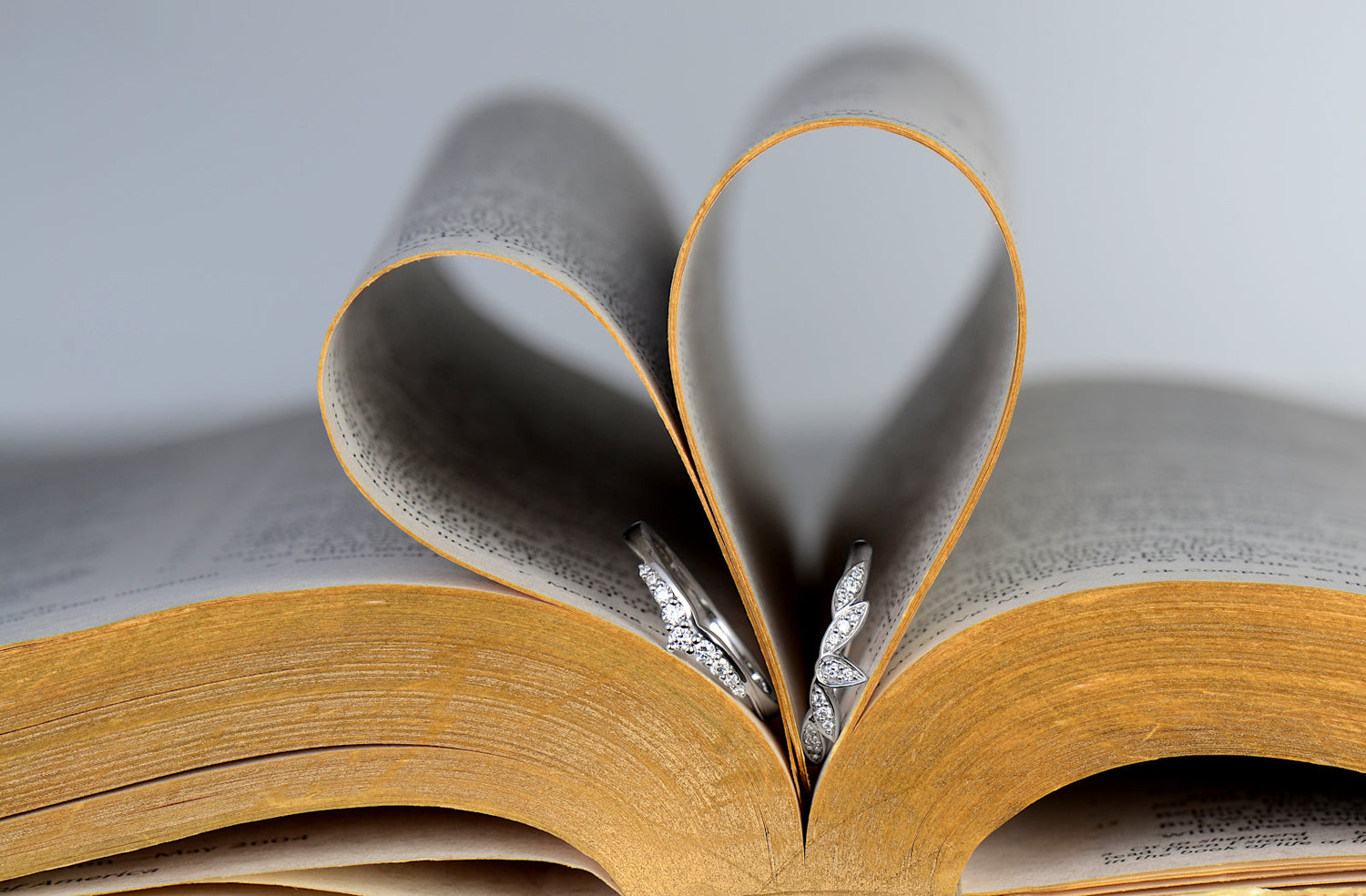 two contemporary diamond wedding rings on a bible that has had the pages lifted to form the shape of a heart