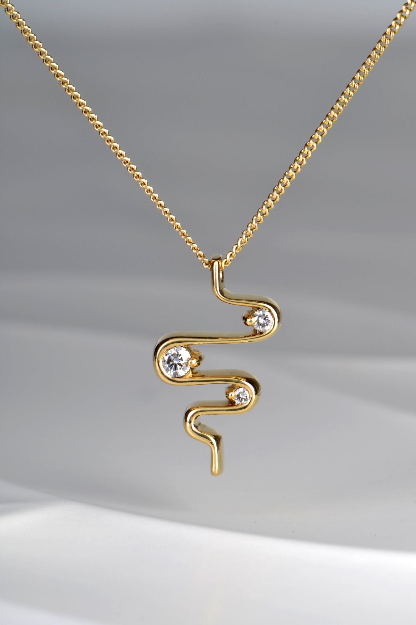 close up of 18ct yellow gold heartbeat three stone diamond designer pendant on 45cm chain