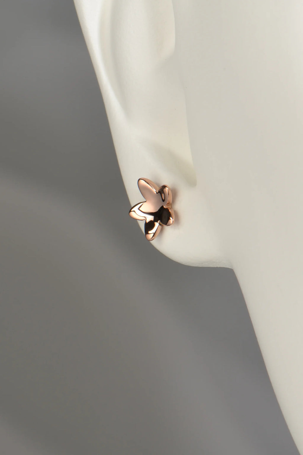 concave 9ct rose gold flower stud earring shown in a mannequin ear for size and scale.