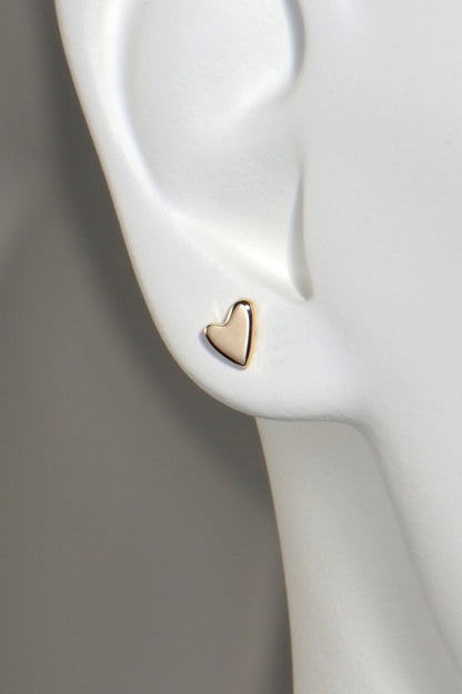 Gold heart-shaped earring on a white mannequin ear