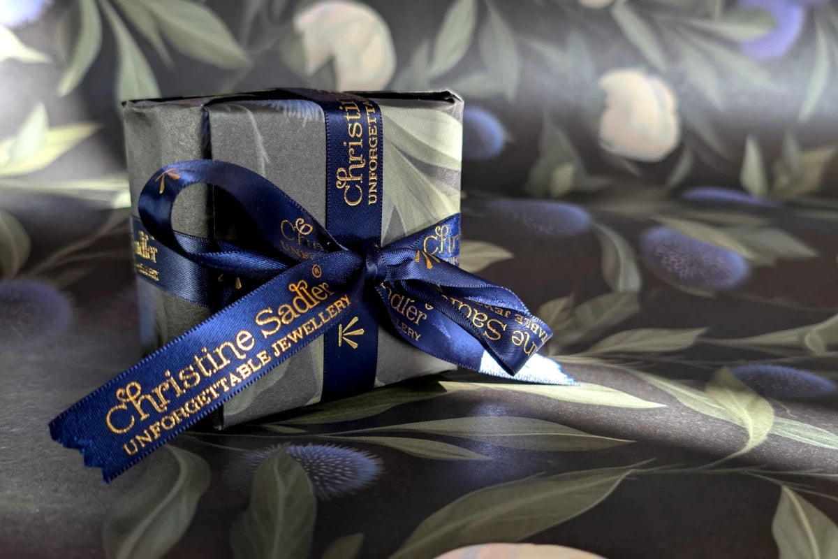New Christine Sadler luxury gift wrapping with thistles and white roses and blue ribbon with gold lettering.