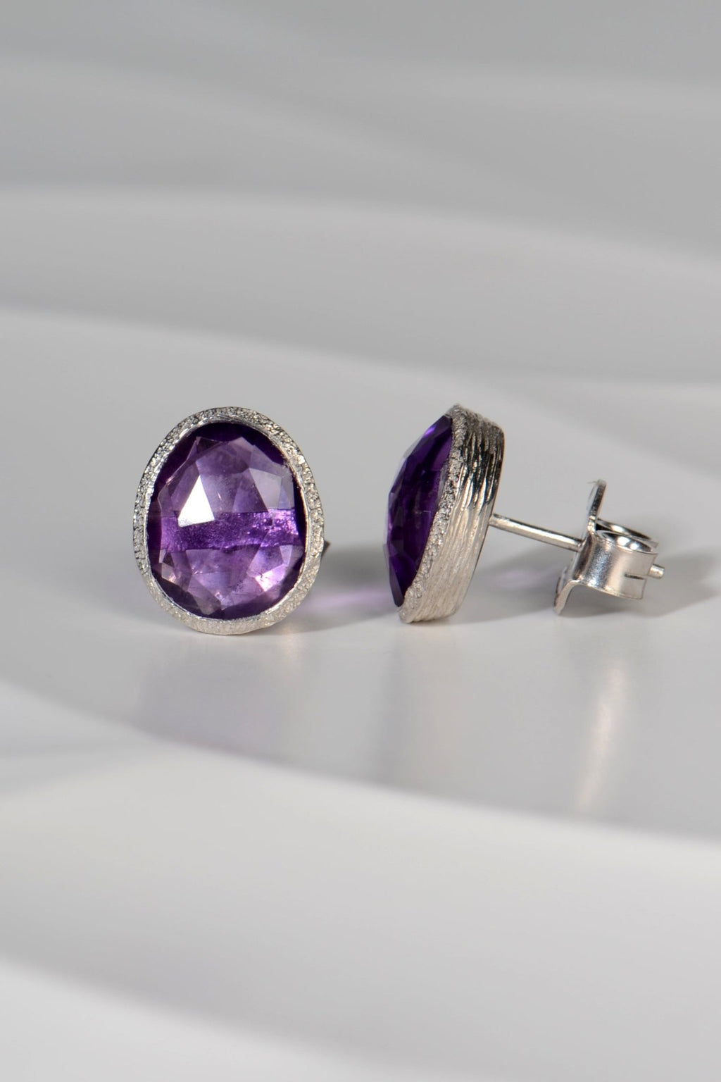 Side view showing sterling silver setting of large amethyst birthstone stud earring