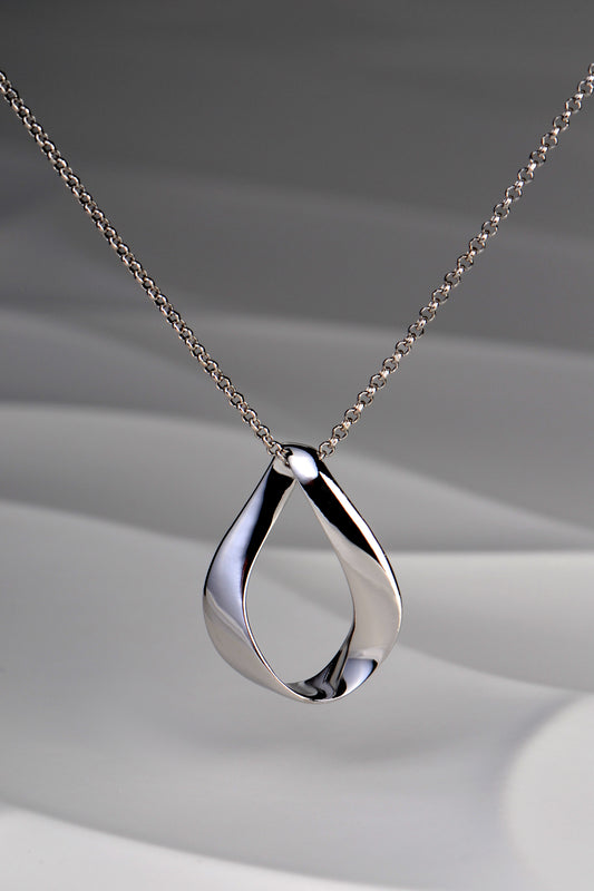 Modern polished sterling silver pendant in a twisted ribbon design that forms a droplet shape with a space in the middle. Like a teardrop shape. This necklace is by Jorge Revilla