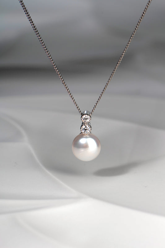 pearl pendant with two round cubic zirconias above it on a silver chain
