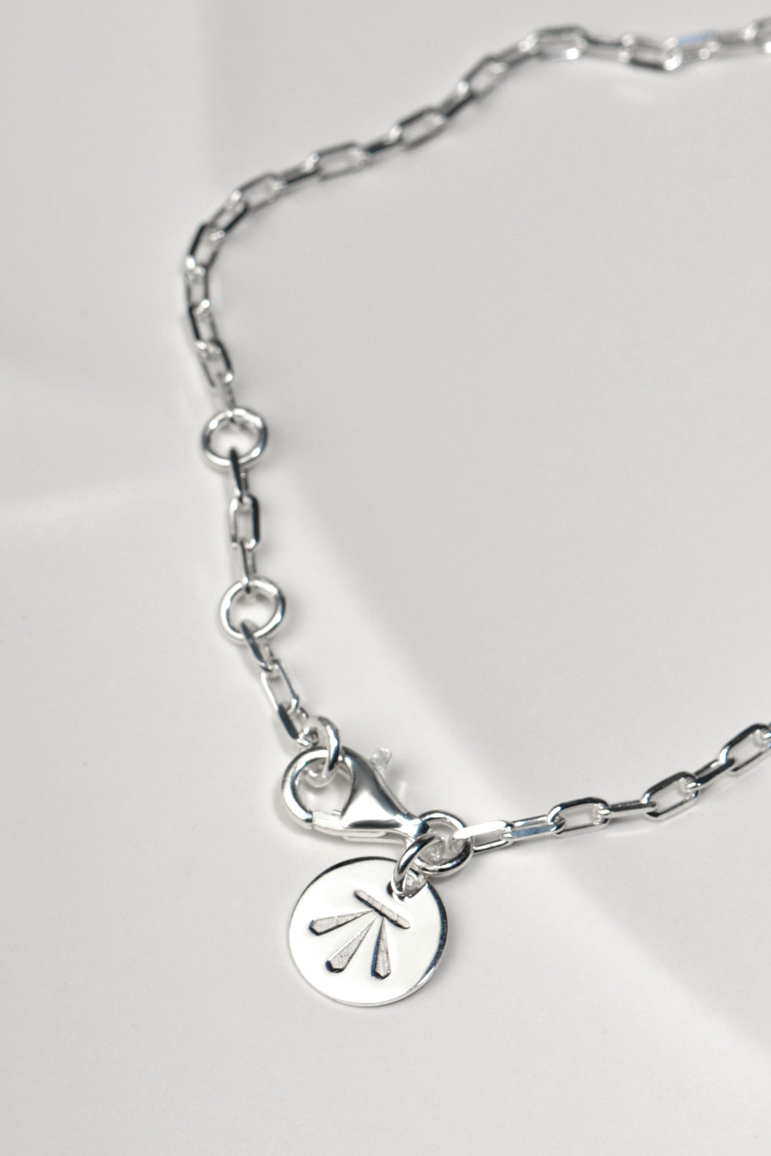 contemporary designer silver bracelet with branded logo tag and three rings in the links that allow the bracelet to be altered in size.