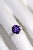 Platinum, amethyst and diamond three stone ring shown on a model for size and scale