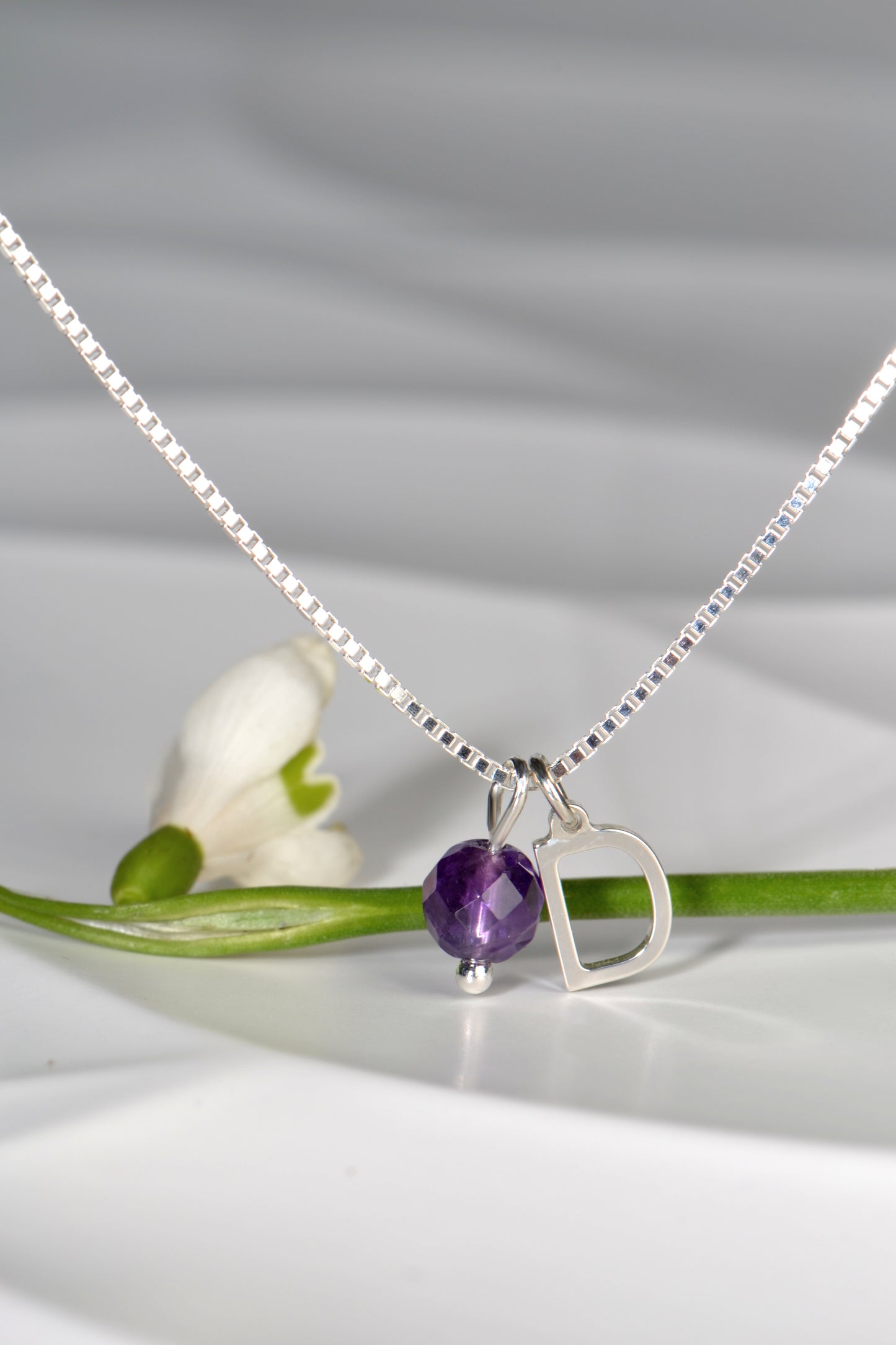 Amethyst initial necklace with snowdrop in the background