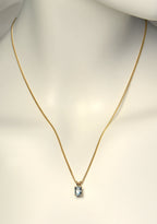 British made 9ct yellow gold radiant cut aquamarine pendant on 9ct yellow gold curb chain on a white mannequin to show length and scale - Christine Sadler