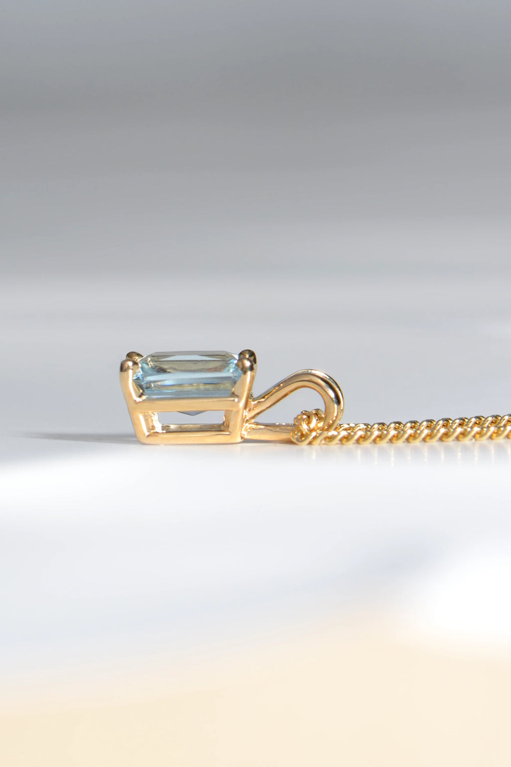 side view of 9ct yellow gold pendant set with a rectangular radiant cut aquamarine in a four claw setting with a double loop bail - Christine Sadler
