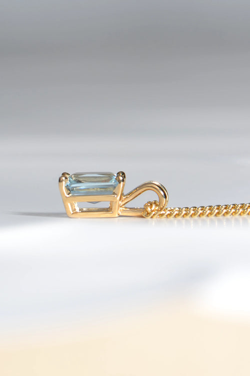 side view of 9ct yellow gold pendant set with a rectangular radiant cut aquamarine in a four claw setting with a double loop bail - Christine Sadler