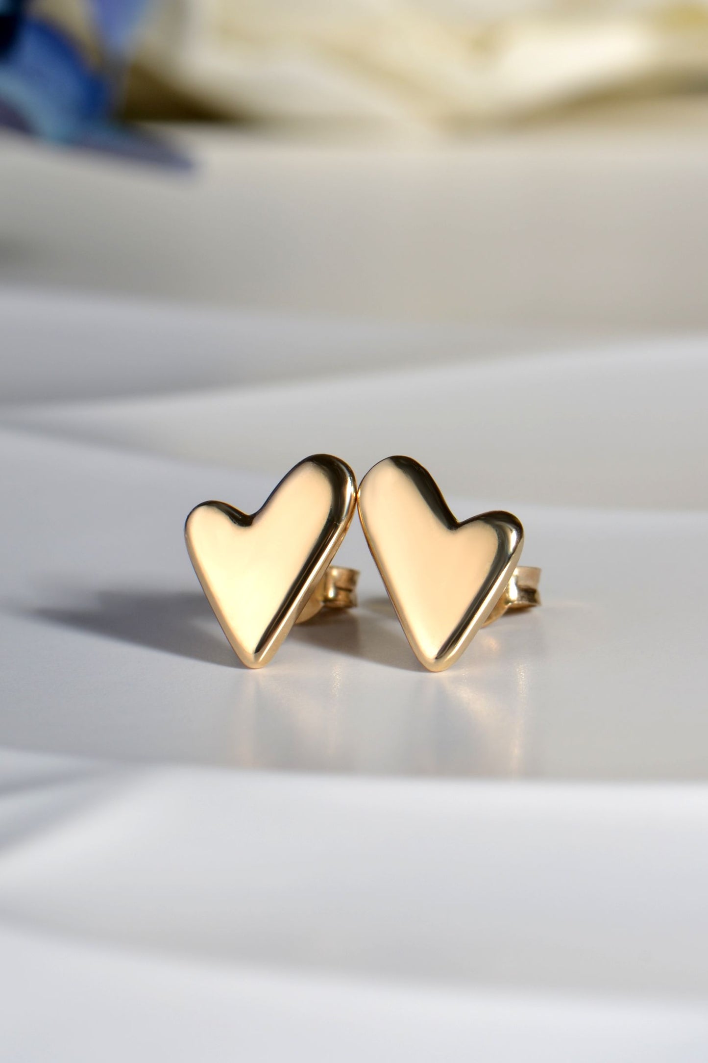 Gold heart-shaped earrings on a light background