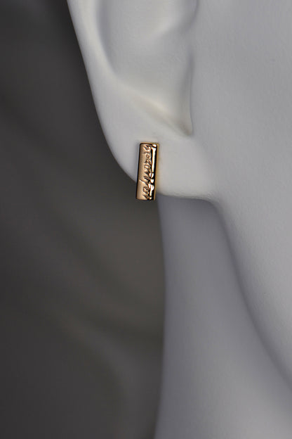 small handmade gold studs that are engraved with the word "beautiful" 