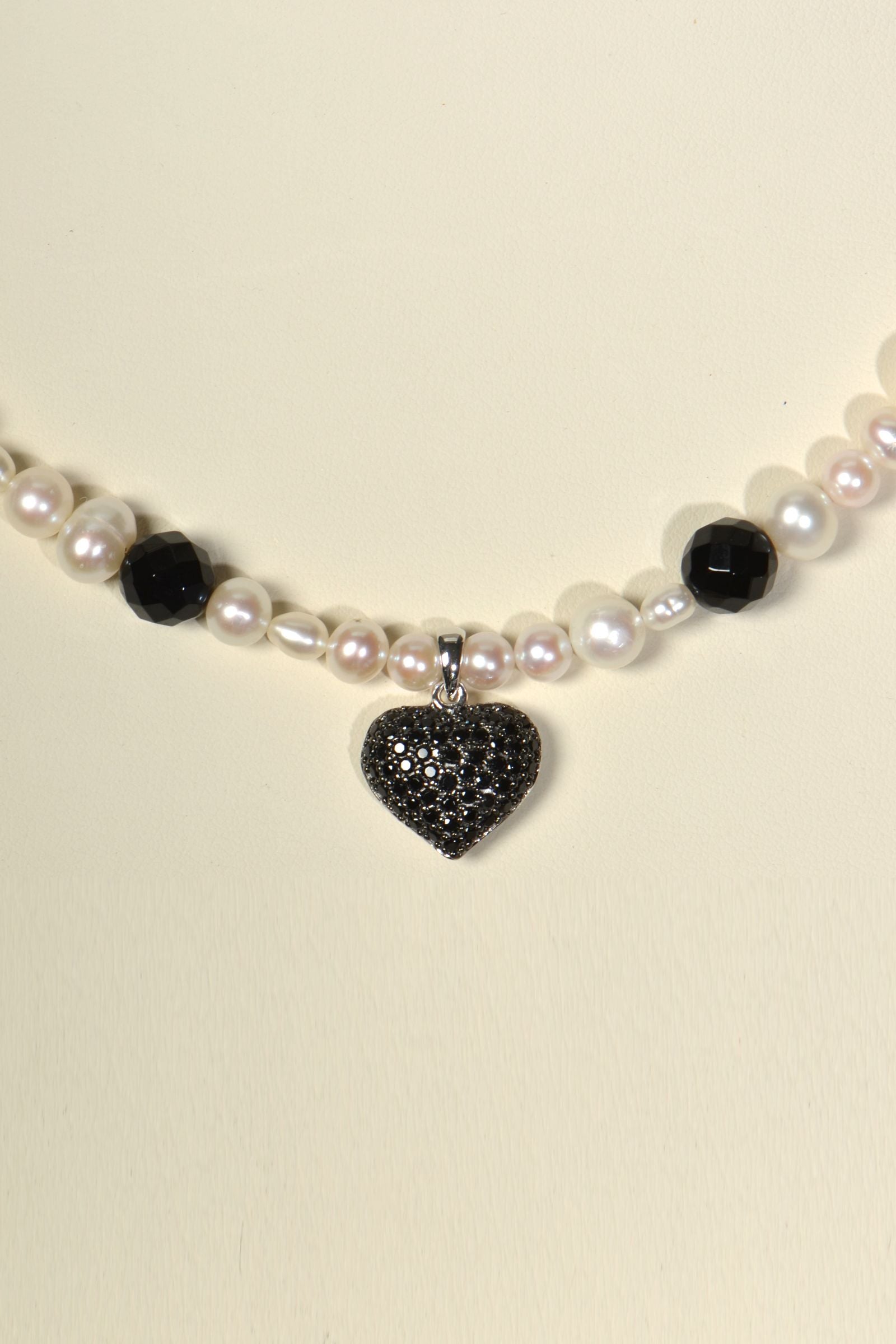 close up detail of the black pave set heart on the white cultured pearl and onyx necklace