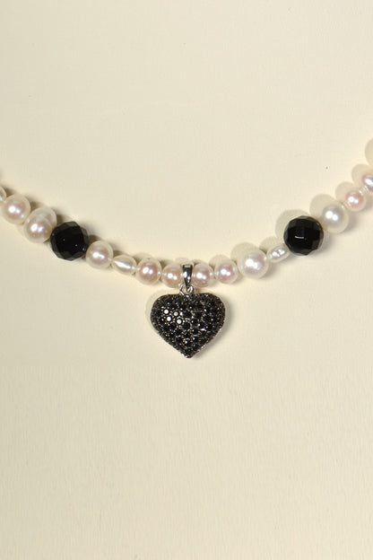 close up detail of the black pave set heart on the white cultured pearl and onyx necklace