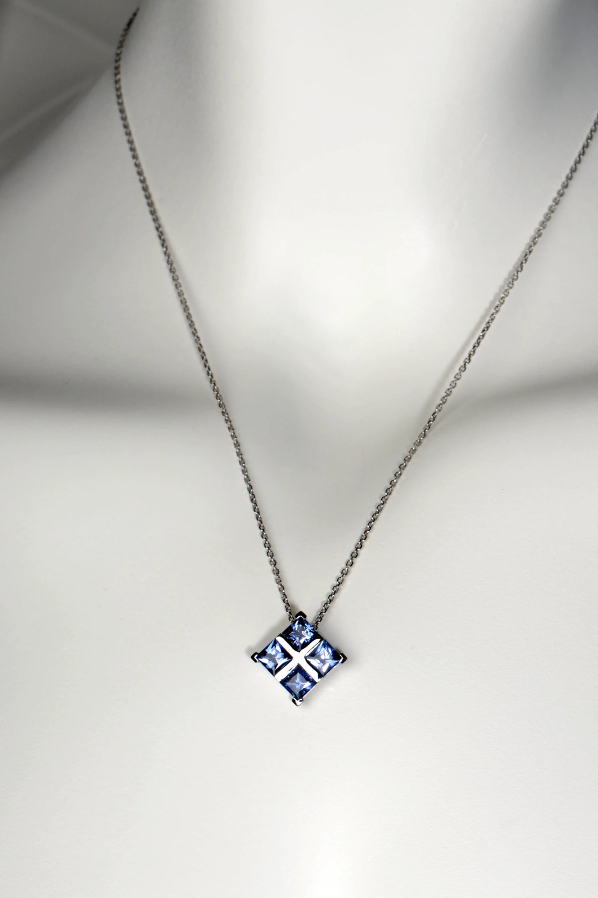 A bespoke platinum and blue sapphire Tartan pendant necklace suspended from a delicate, light-catching filed trace chain.
