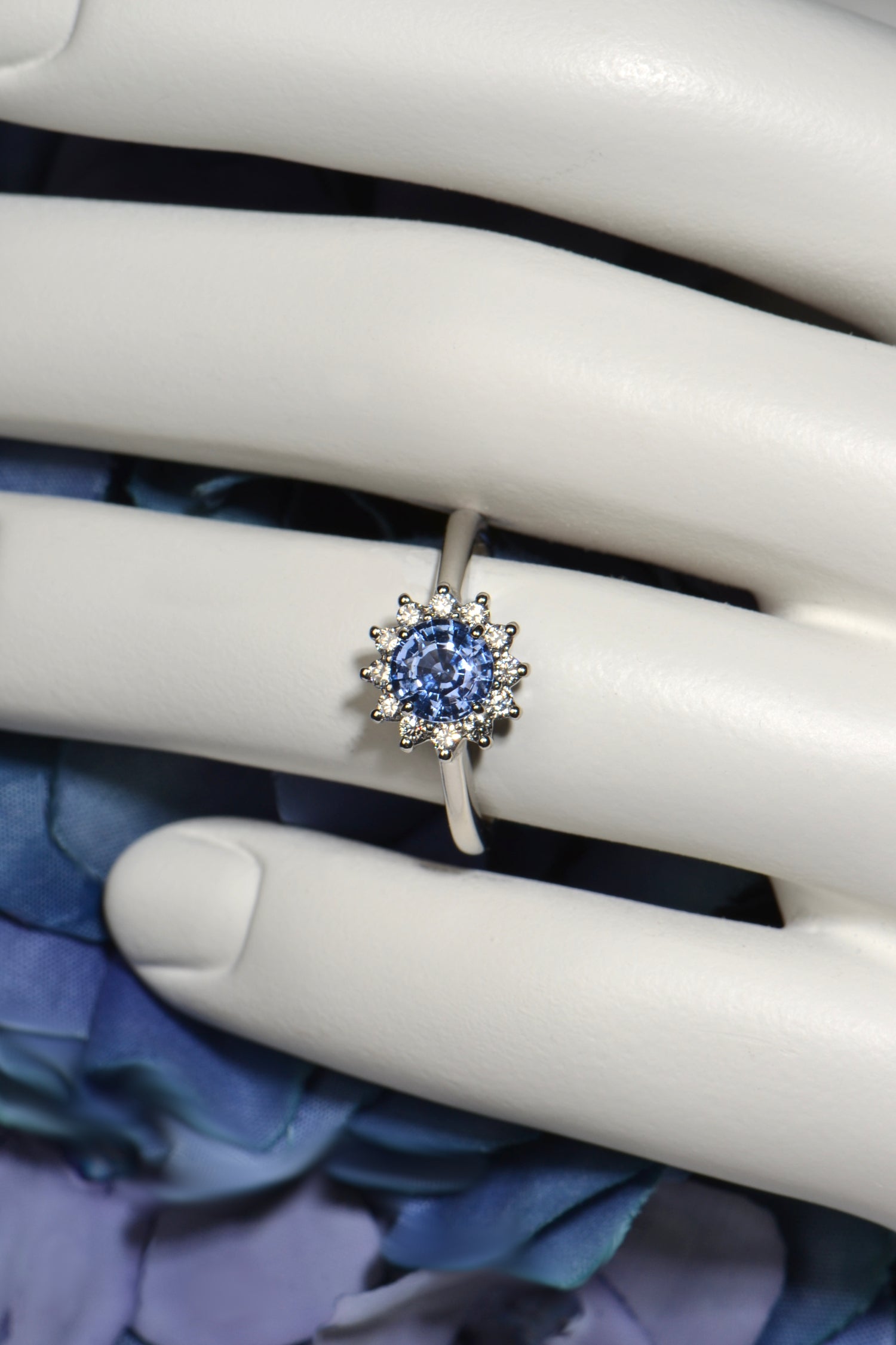 Luxury platinum sapphire and diamond flower ring symbolising love and unity shown on white mannequin hand