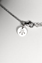 silver necklace with Christine Sadler's Benchmark logo