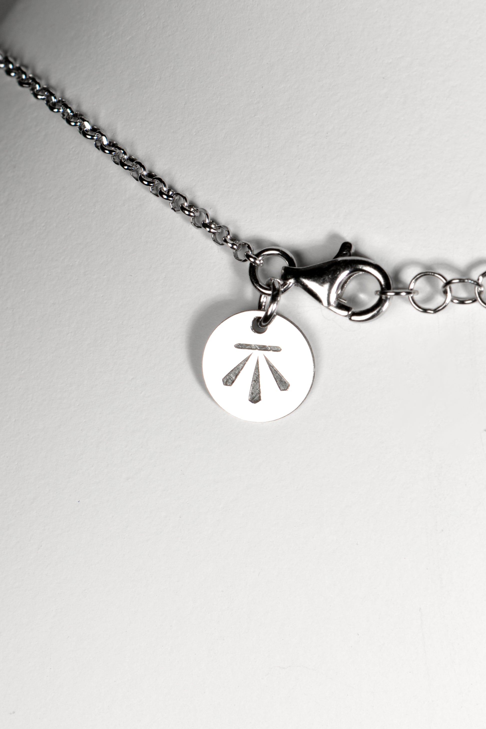 silver necklace with Christine Sadler's Benchmark logo