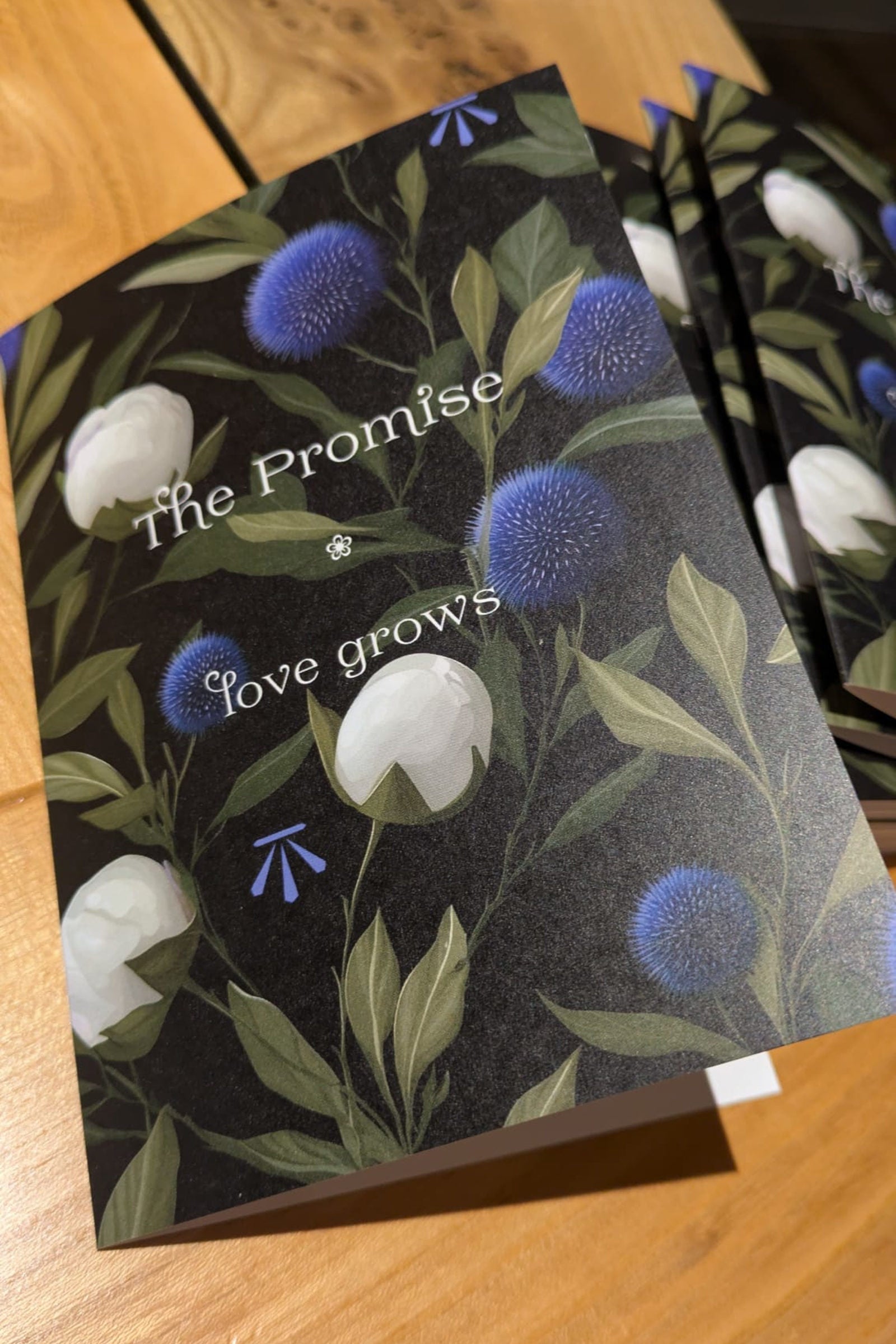 Card with floral design and text 'The Promise love grows' on a wooden surface Christine Sadler